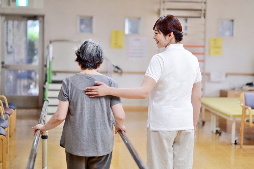 高齢女性の背に手を添える介護士の女性.jpg
