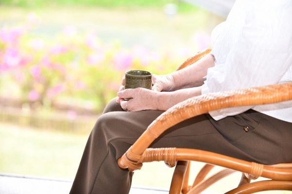 籐椅子でお茶を飲む高齢女性